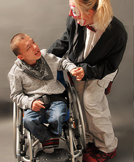 Unterhaltungskünstlerin Sandra belustigt ein Kind im Rollstuhl.